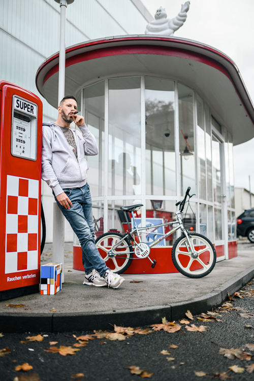 Andreas John mit BMX-Rad an einer historischen Tankstelle
